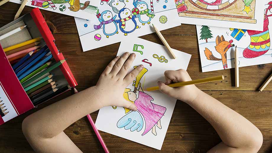 bambina a scuola disegna con pastelli